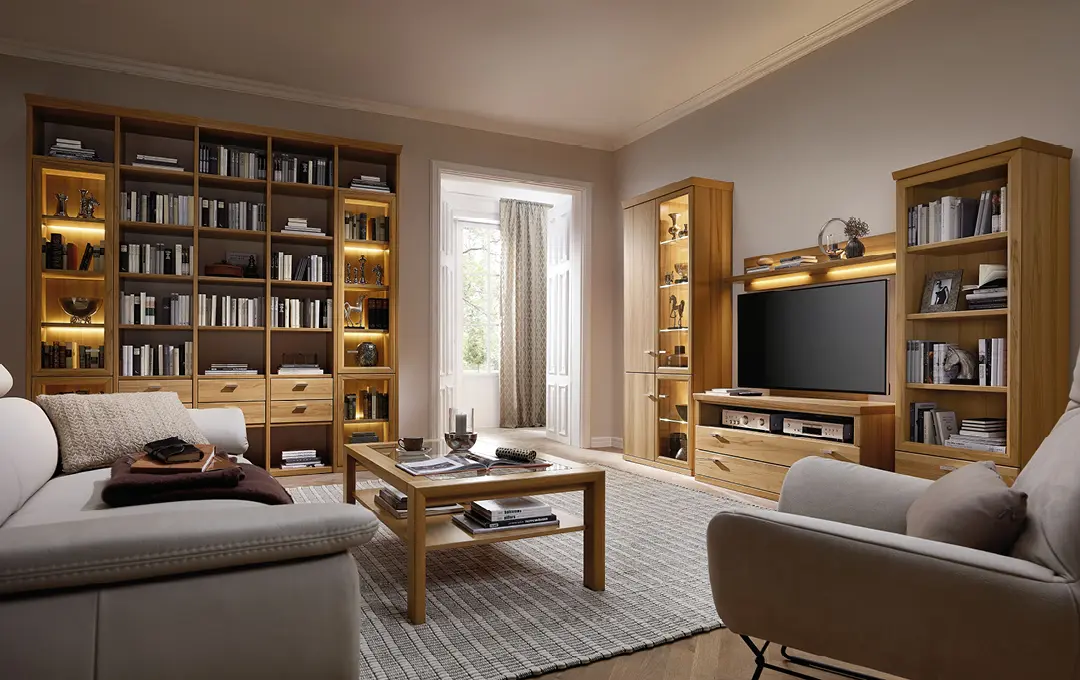 Wohnzimmer mit Bücherregal, TV-Möbeln aus Holz, Vitrinen, Couchtisch und Sesseln